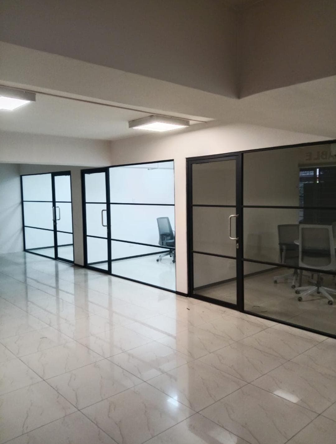 Glass cabin partition with a hinged door in an office