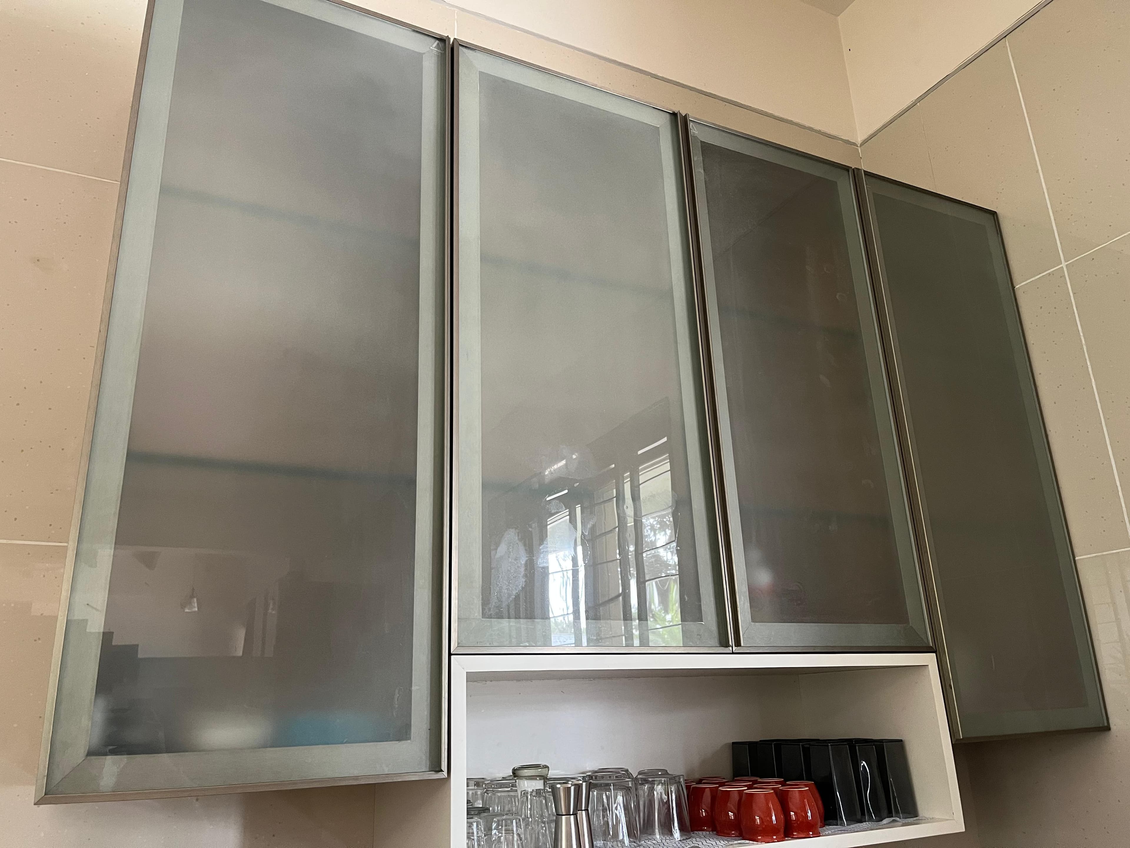 Frosted glass shutters in aluminium frames on a fitted kitchen wall cabinet