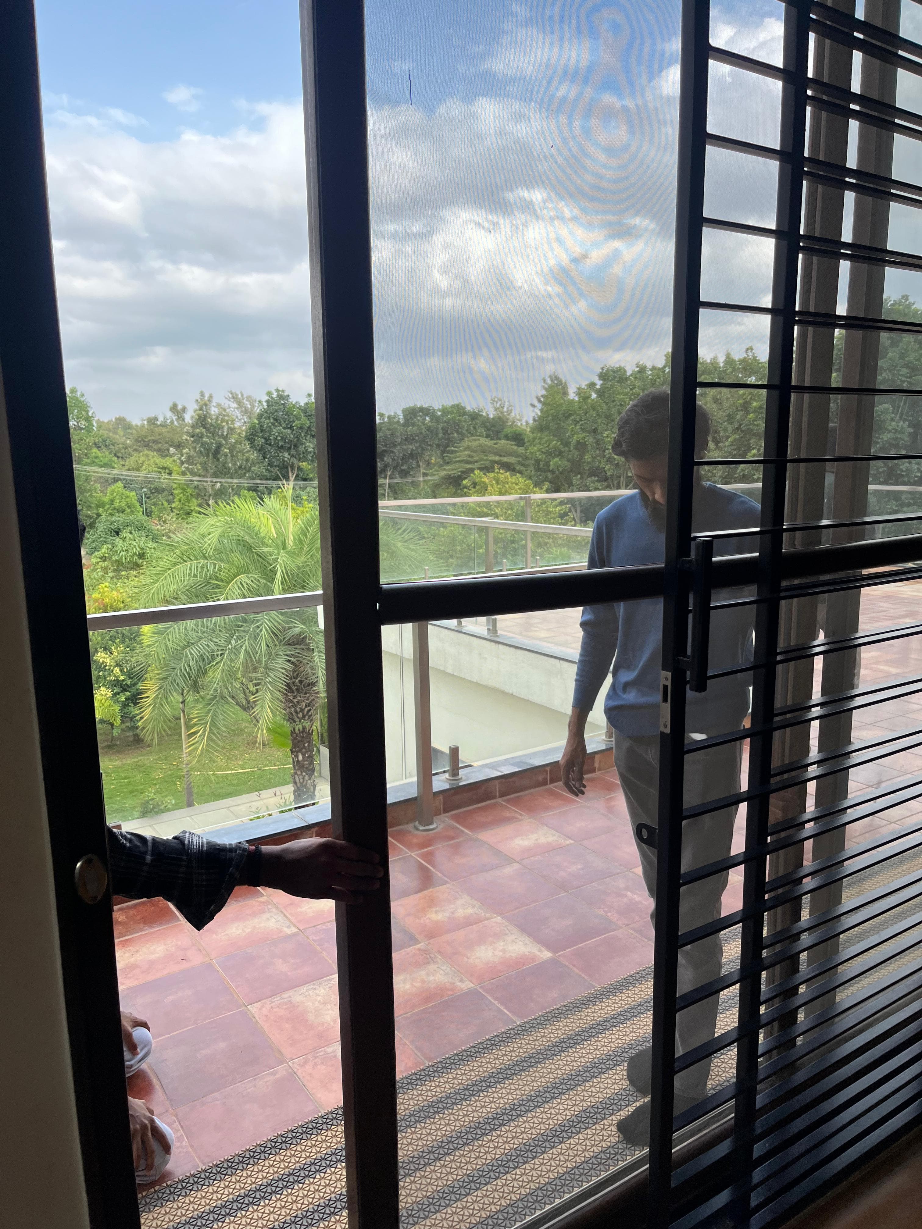 Two fitters at an aluminium sliding door and its mesh screen, open on to a balcony